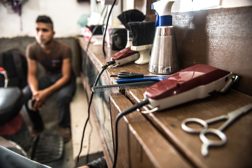 Rokam Hamoud cuts a customer’s hair in his barber shop in Husseini. The shop was looted by ISIS in 2014, but support from Oxfam has helped him to rebuild the business. credit-tommy-trenchard_oxfam-may-2016-2