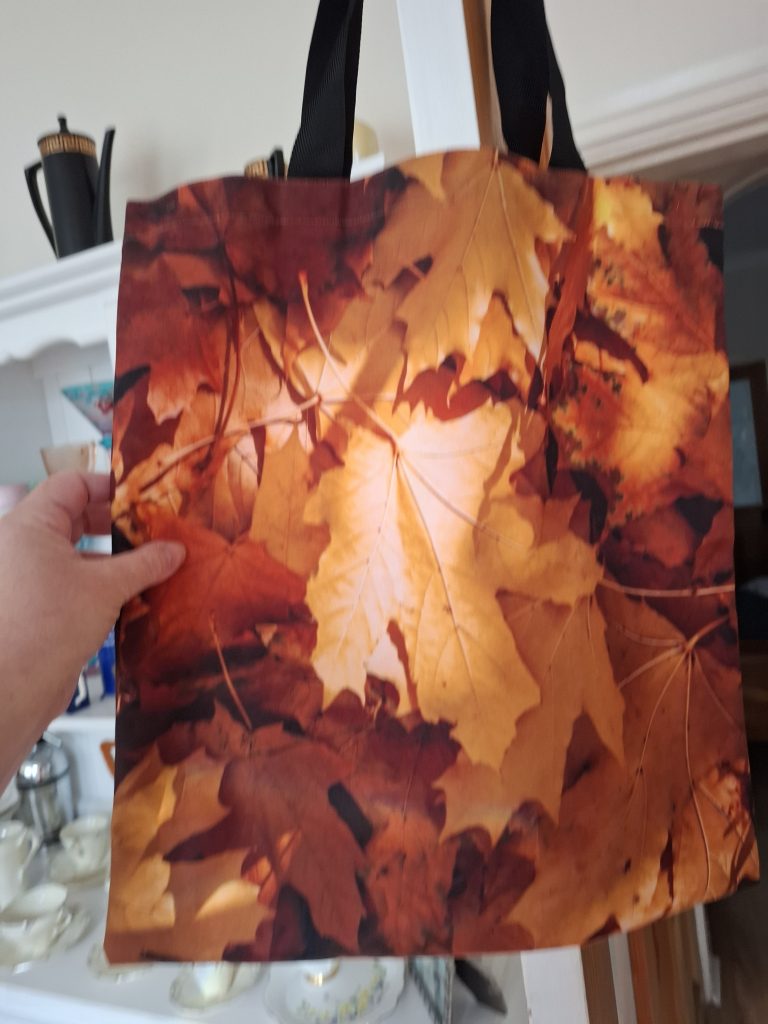 A tote bag with autumn leaves all over it